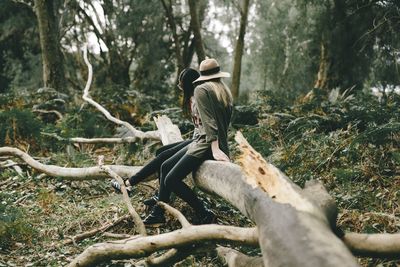 Woman sitting on tree trunk in forest