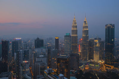 Illuminated cityscape against sky at dusk