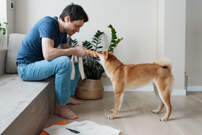 Funny adult man playing with a homemade dog toy with his favorite furry dog friend