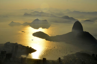 Aerial view of boats in sea by sugarloaf mountain and city during sunrise