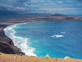 View over the beach and bay at famara, lanzarote, with volcanic hills in the background