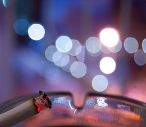 Close-up of cigarette against defocused lights at night