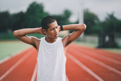 Portrait of young man exercising on field