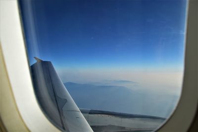 Airplane flying in sky seen through glass window