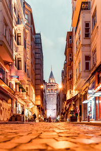 People on street amidst buildings in town against sky in city