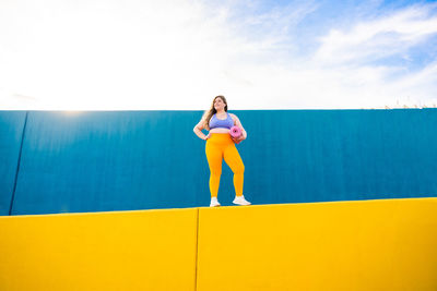 Full length of young woman standing against wall