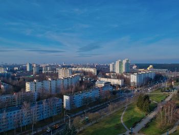 High angle view of buildings in city against blue sky