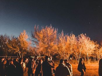 Group of people by tree during autumn against sky