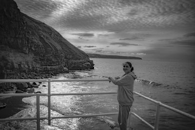 Portrait of woman standing by railing against sea