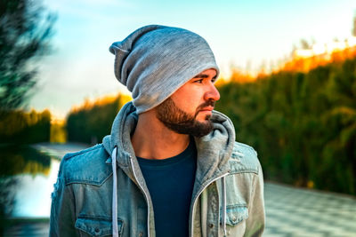 Portrait of man looking away against sky during sunset