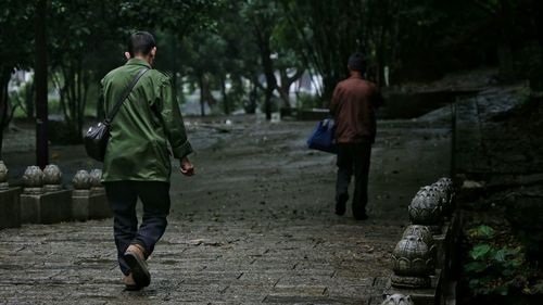 Rear view of men walking on footpath