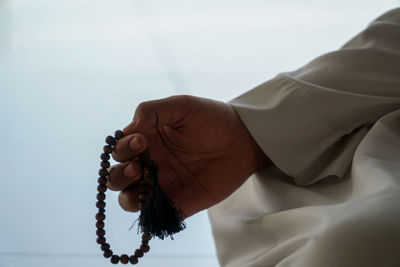 Cropped image of person holding prayer beads