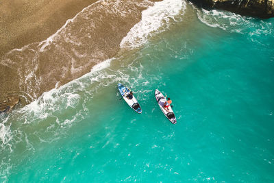 Top down aerial view of man and woman paddling on stand up paddle boards