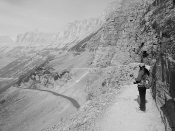 Rear view of man standing on road against mountain range