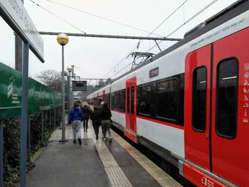 People on train at railroad station against sky