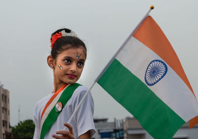 Cute indian girl kid holding indian flag celebrating indian independence day showing patriotism. 