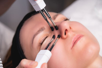 Close-up portrait of a beautiful woman with closed eyes and a skin rejuvenation machine. salon