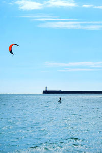 Person paragliding in sea against sky