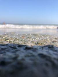 Surface level of sea shore against clear sky