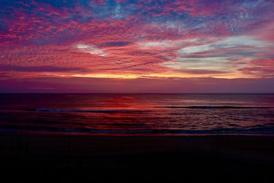 Scenic view of sea against cloudy sky during sunset