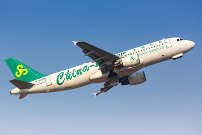 Low angle view of airplane flying against clear blue sky