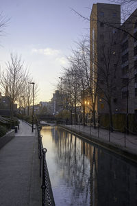 Canal amidst buildings against sky at sunset
