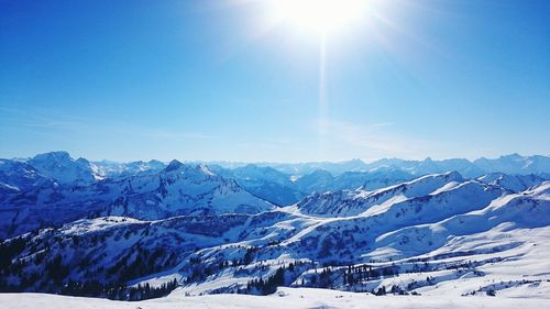 Scenic view of snowcapped mountains against blue sky