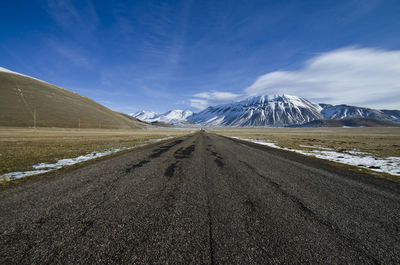 Road leading towards mountains against sky