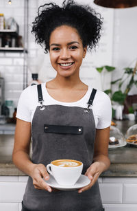 Portrait of smiling woman holding coffee in restaurant