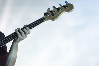 Cropped hand of man playing guitar against white background