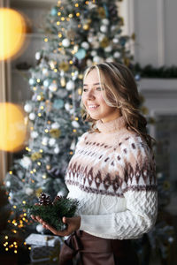 Happy cute girl in a cozy sweater celebrates christmas prepares gift boxes at home indoor