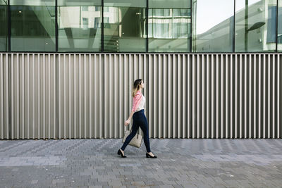 Full length of woman standing on footpath in city