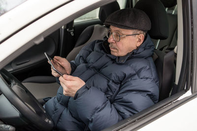 Midsection of man using mobile phone while sitting in car