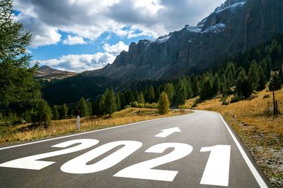 Road sign by mountains against sky