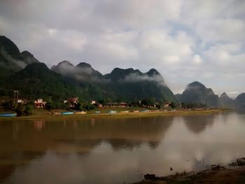 Scenic view of lake and mountains against cloudy sky