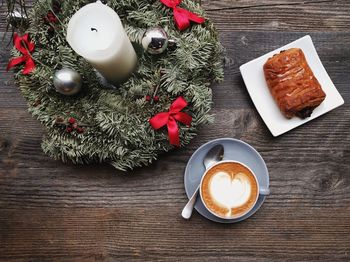 High angle view of cappuccino and dessert by wreath on table