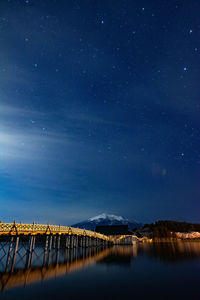 Scenic view of pier on lake against sky at night
