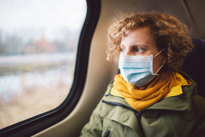 Woman wearing mask sitting in train