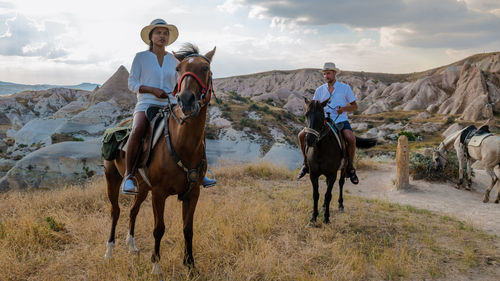 Rear view of man riding horses on field