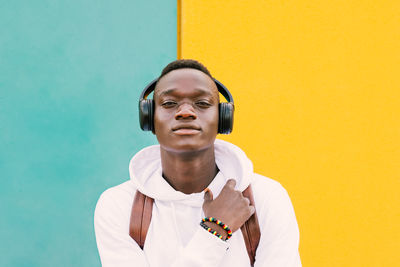 Portrait of young man standing against colored wall