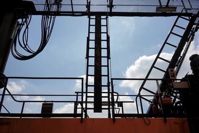 Low angle view of silhouette cranes against sky