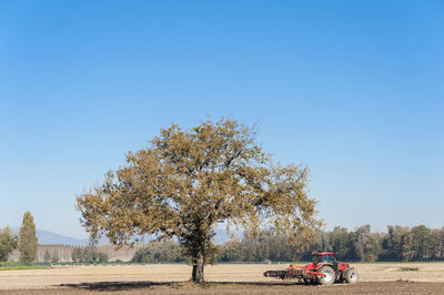 Tractor on agricultural field against clear blue sky