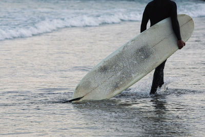 Young surfer with surfboard on the sea shore