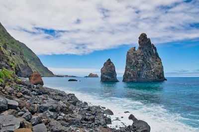 Rocks on sea shore against sky