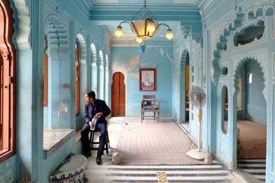 Full length of man sitting on chair in corridor