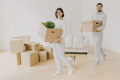 Couple carrying boxes while walking in new home