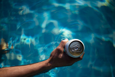 Selective focus white beer can in hand. man is soaking in the pool with an open beer can relax 