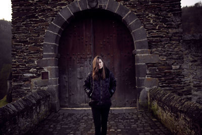 Portrait of woman standing against building