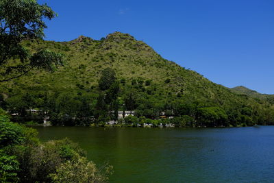 Scenic view of lake and trees against clear blue sky