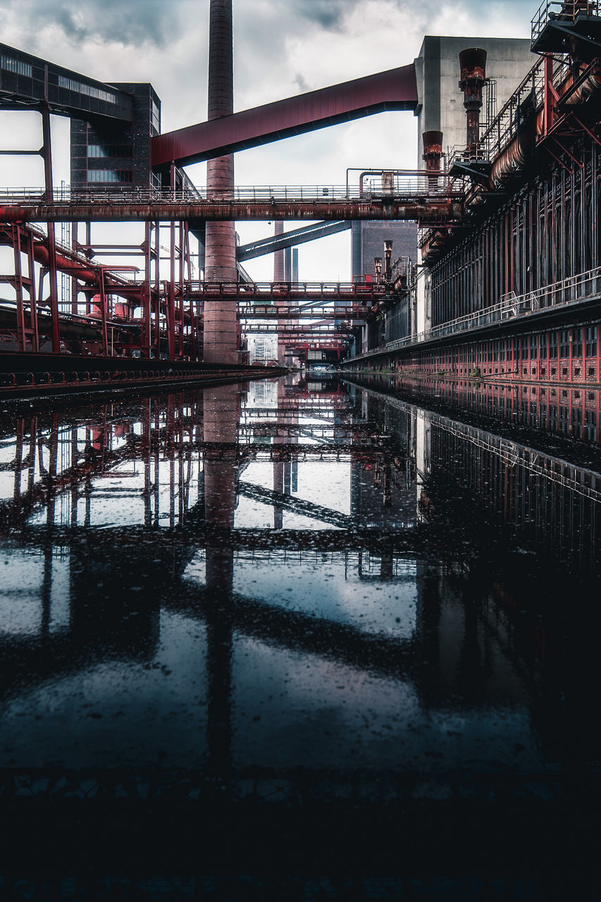 reflection, architecture, water, built structure, sky, cloud, bridge, nature, urban area, industry, transportation, building exterior, no people, outdoors, city, transport, railing, river, metal, day, waterway